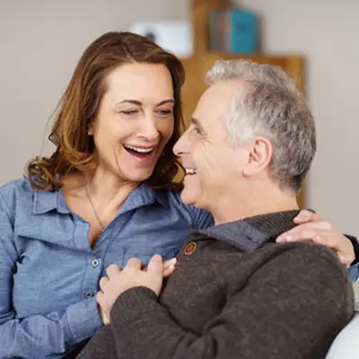 Man und Frau fröhlich auf einer Couch lächeln sich an | Adobe Stock #110276517 contrastwerkstatt