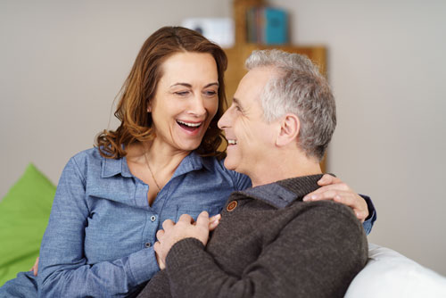Man und Frau fröhlich auf einer Couch lächeln sich an | Adobe Stock #110276517 contrastwerkstatt